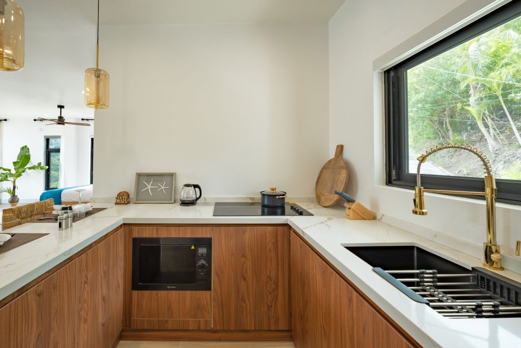 Harbour Villa 1 kitchen with a gold tap and a window onto the trees