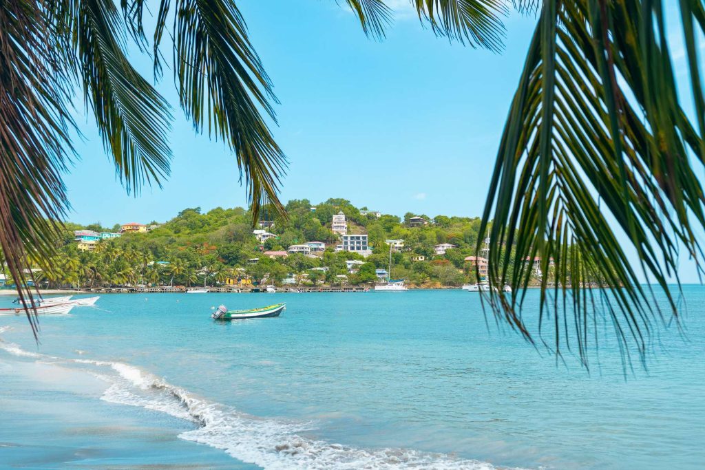 Laborie beach framed by palm fronds, a fishing boat in the bay