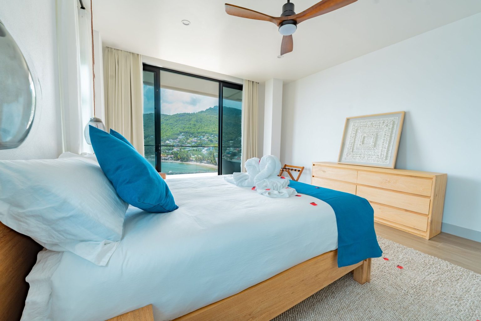 Freshly made Penthouse bed with folded towel swans and blue cushions