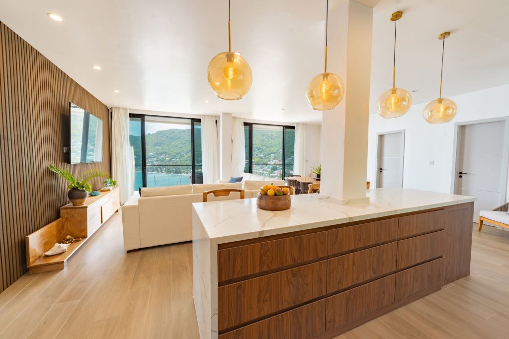 Walnut and marble kitchen island under amber pendant lights in the Penthouse